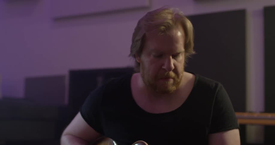 A man rocks his head as he plays a guitar