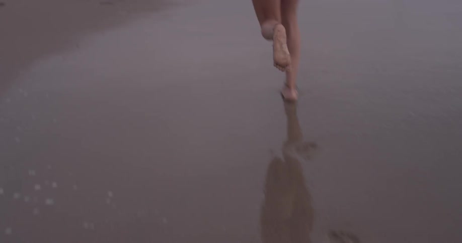 Woman running down the beach at the edge of the water