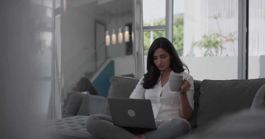 A woman sitting on the couch with a laptop on her lap