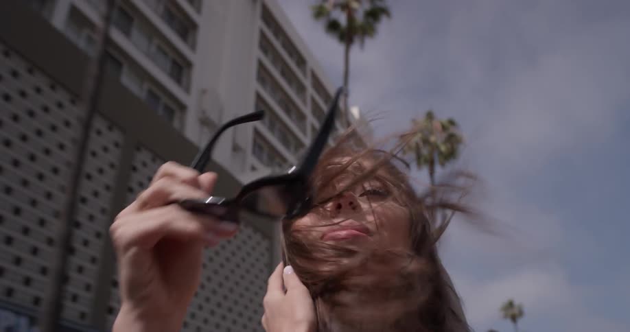 Woman rides in a convertible pushing her hair back