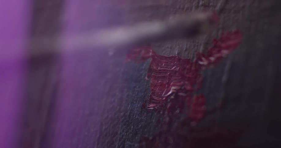 A person painting with some red paint