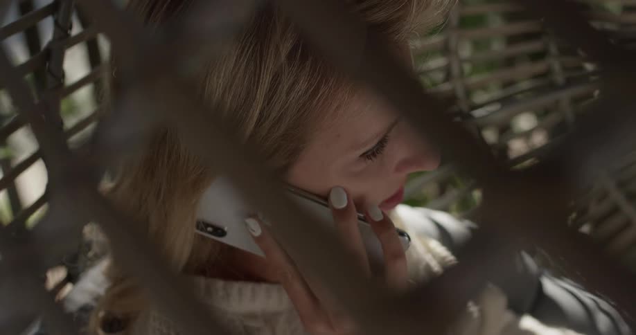 A woman sitting in a swing talking on the phone