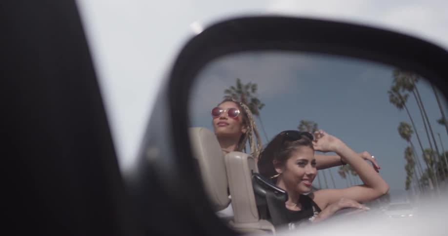 Two women dancing in the back of a convertible