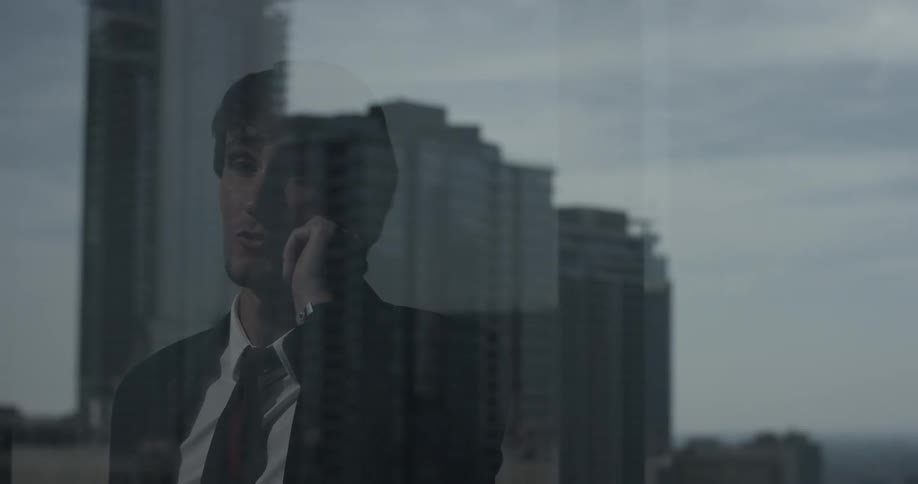A man walks to the window talking on the phone