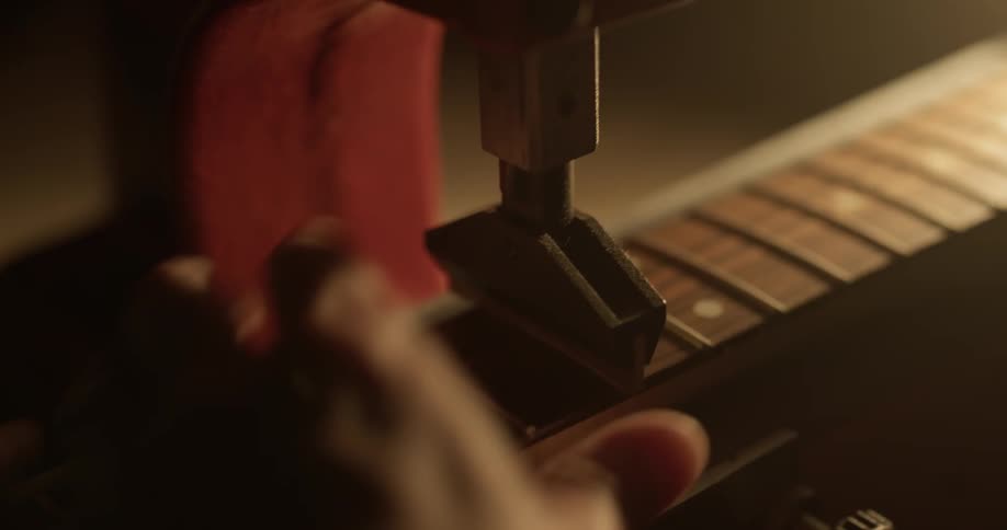 A person repairing the frets on a guitar