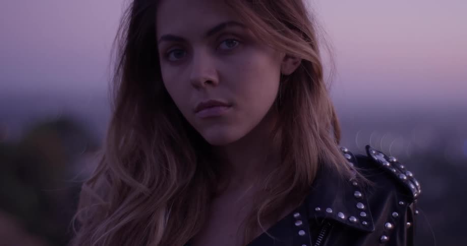 A woman wearing leather stares in the distance