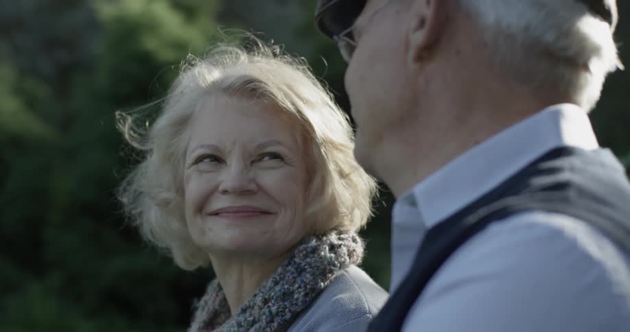 A woman is smiling at a man outdoors