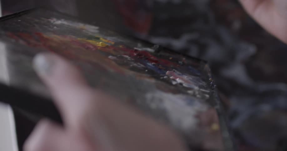 A woman with blonde hair painting on a canvas