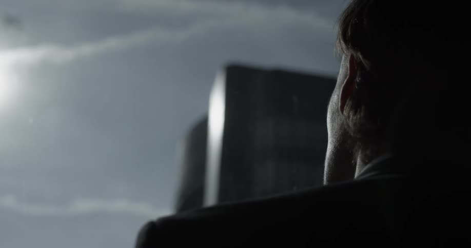 A man looks toward the cloudy sky with a bit of sun visible