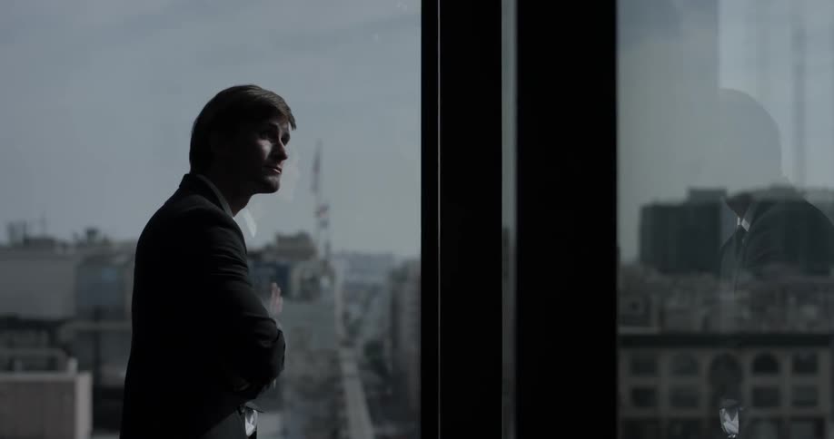 Man wearing a suit staring out a large window