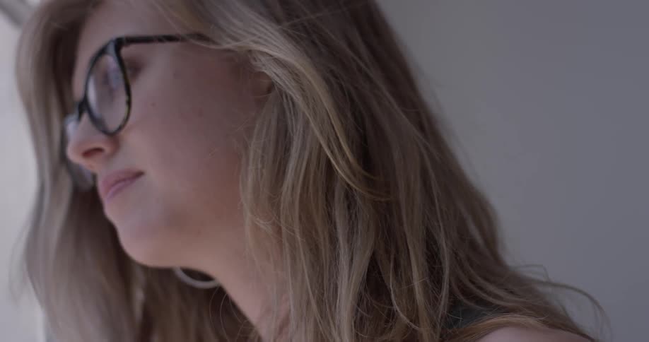 A woman in glasses looking out a window