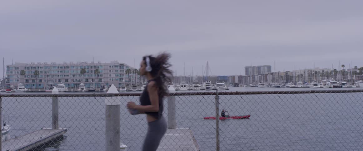 A woman is jogging and a person is kayaking