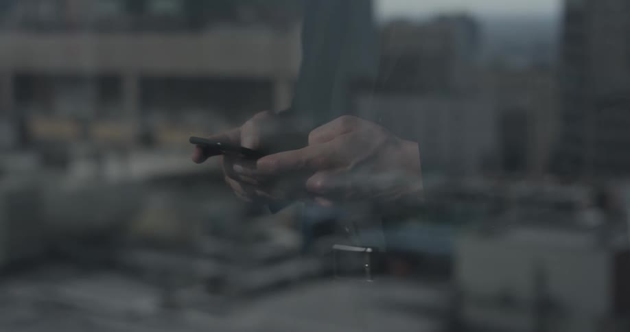 A person standing using their phone to text