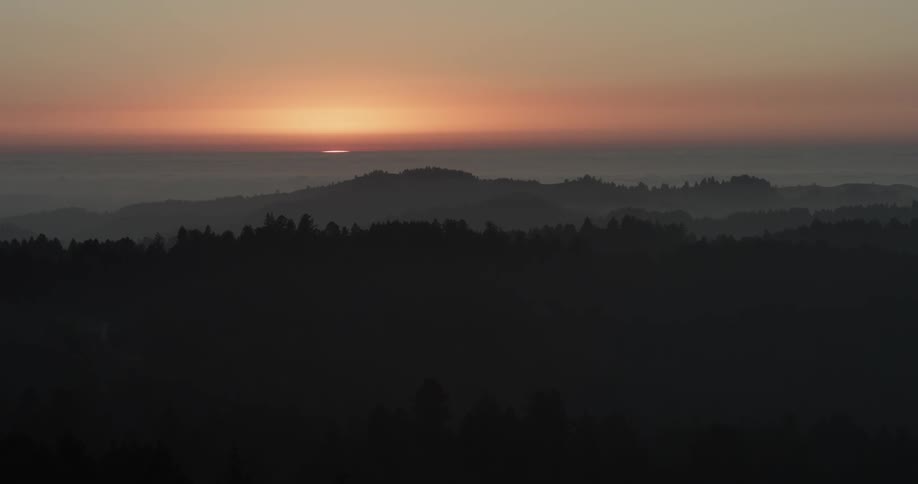 Time lapse of the sun setting on a nice slightly cloudy day over a range of mountains and trees
