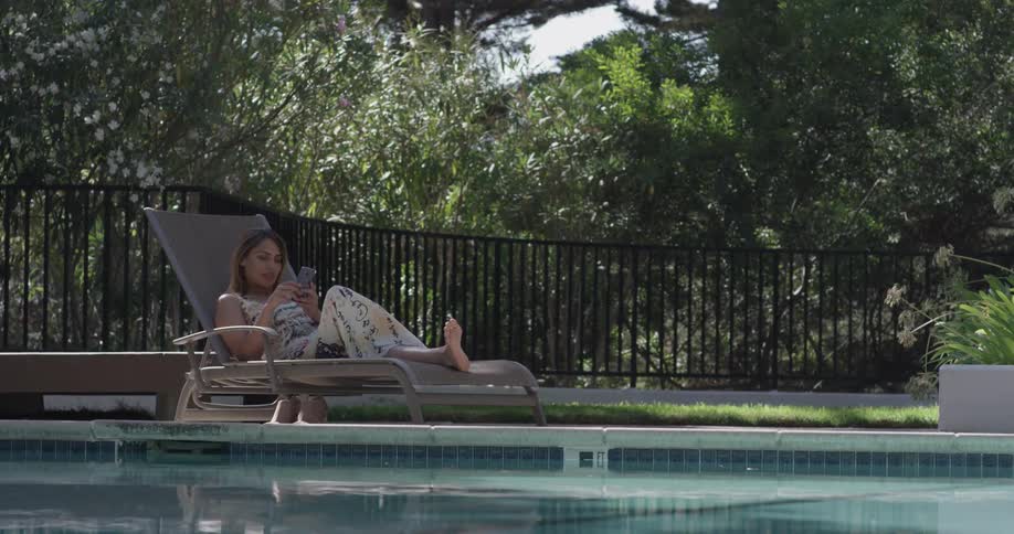 A woman lounges in a chair by the pool