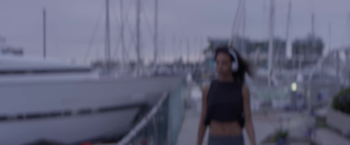 A woman is jogging outside by boats