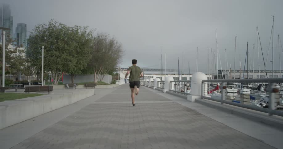A man running down a pier next to a marina