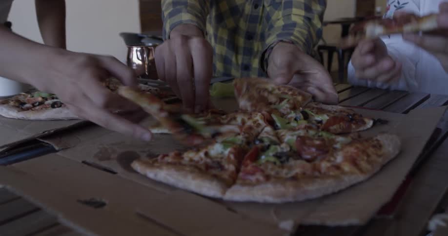 A man is eating pizza with friends