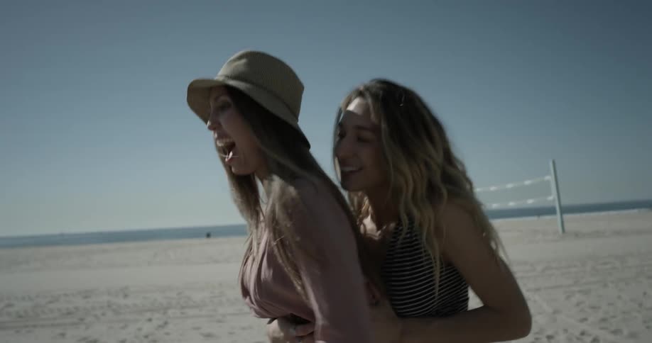Two women ride on scooter near beach
