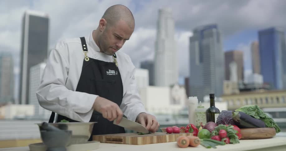 Chef chopping vegetables outside in a city