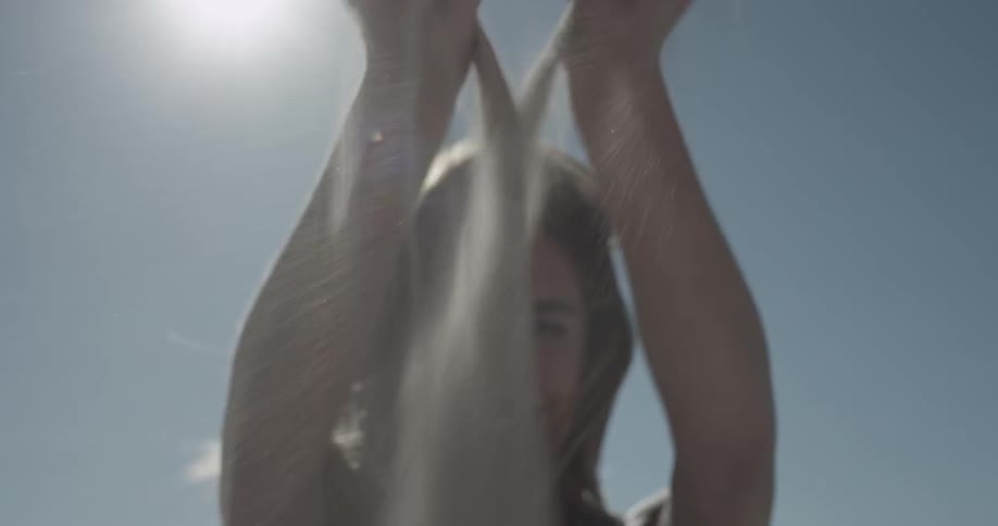 Woman smiles and plays with sand in the sunlight