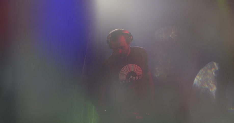 Man puts on headphones and puts record into player in a club