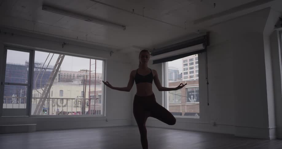A woman does yoga in an empty room