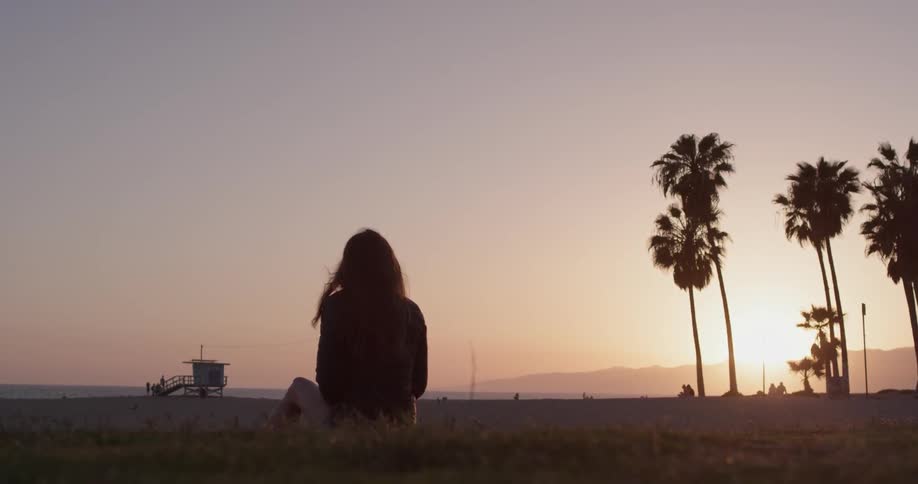 Woman sitting on the beach watching the sunset
