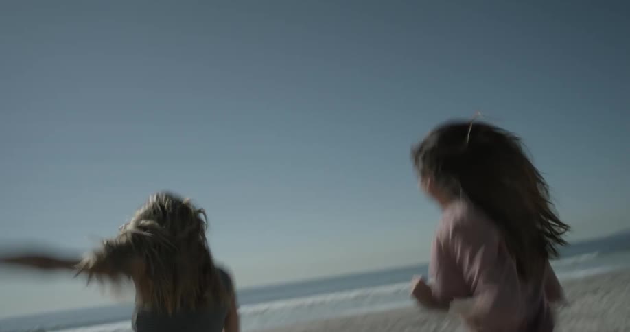 Two women run towards the beach