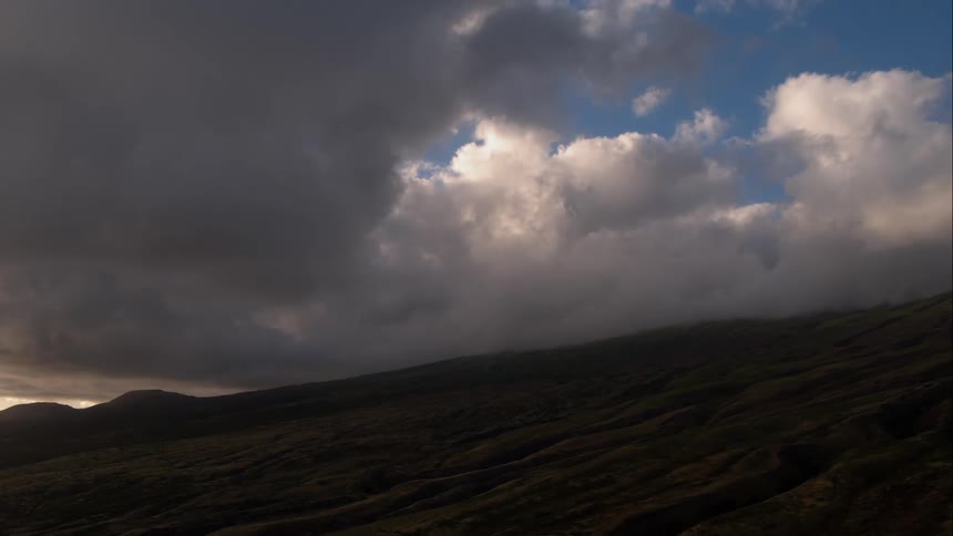 Dark gray clouds roll over hills