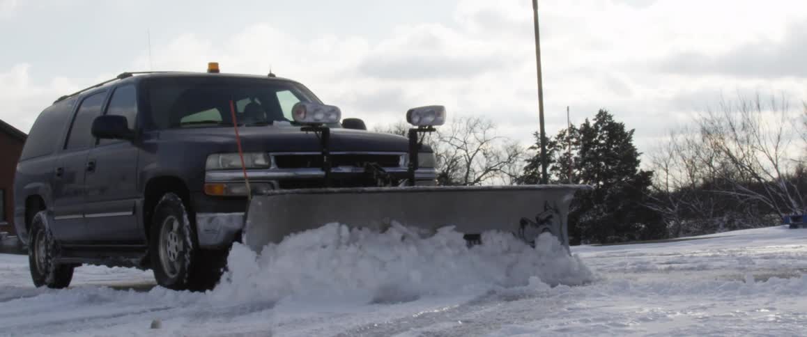 A truck is going down the snow covered street