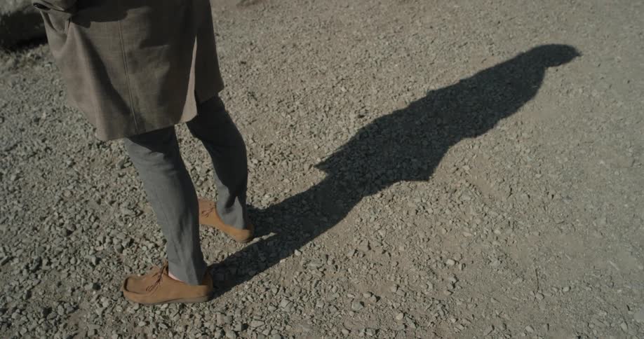 A person stands on dirty rocky ground