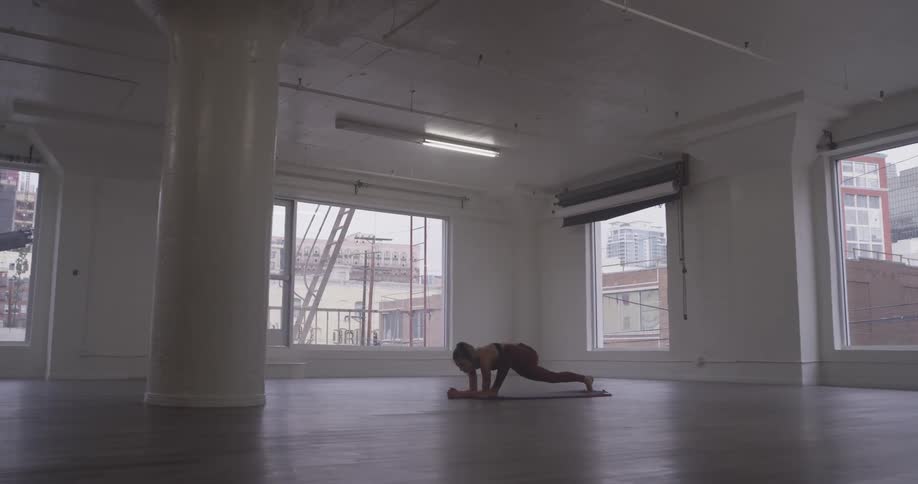 Woman practices yoga poses in an empty room