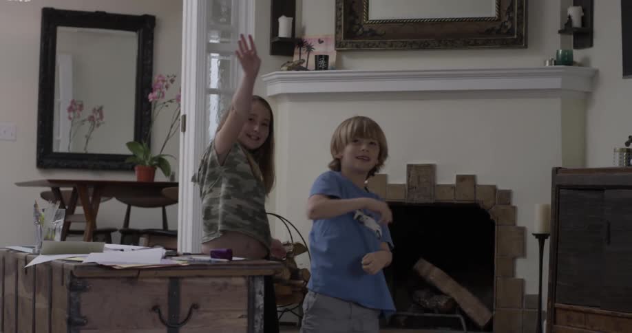 Two children throw paper airplanes in a living room