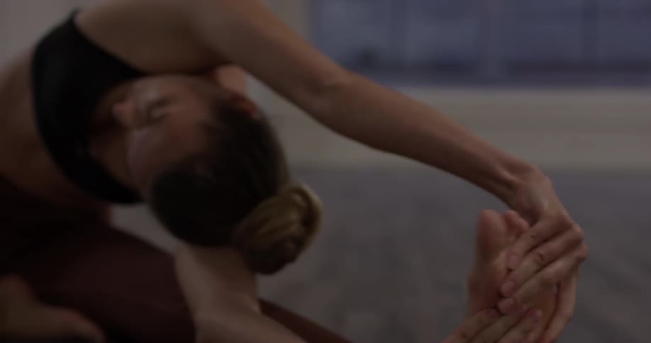 Woman stretches on a mat in an empty room