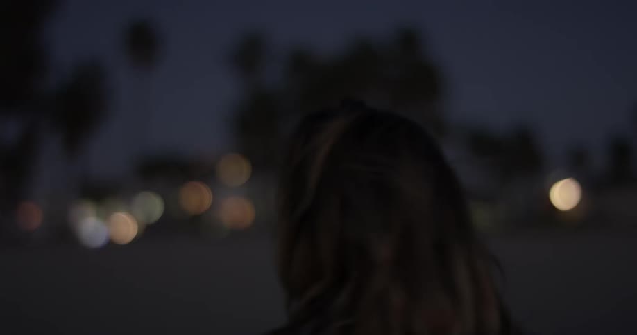 A woman walking on the beach at night