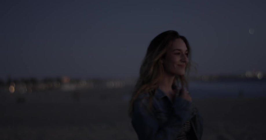 A woman smiles, turns around, and stretches her arms out