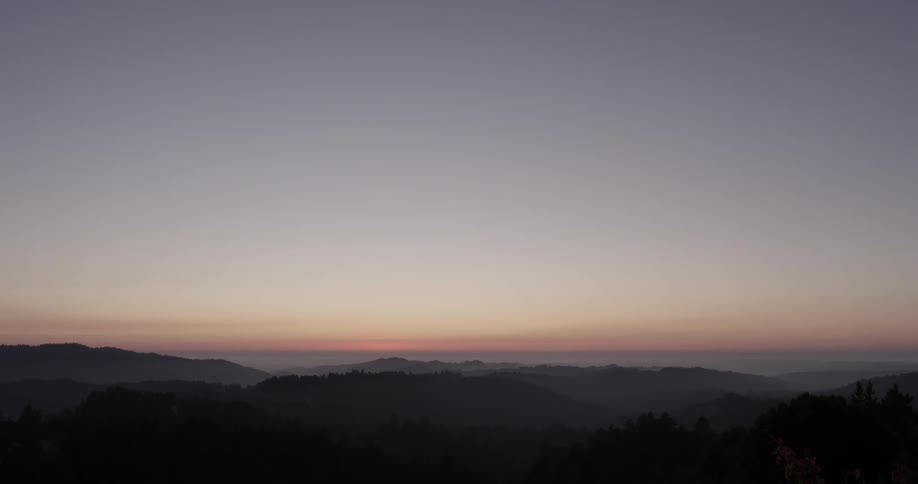 The sun sets behind mountains