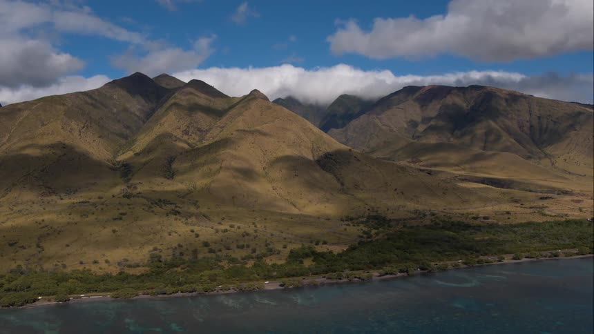 Aerial view of a coastal highway with mountainous terrain in the background