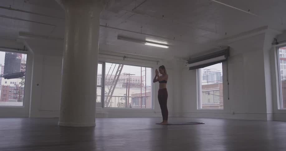 A woman stretches in an empty studio