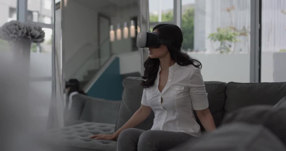 Woman sitting on a couch putting on a virtual reality headset