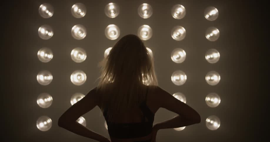 A woman walks towards large light bulbs