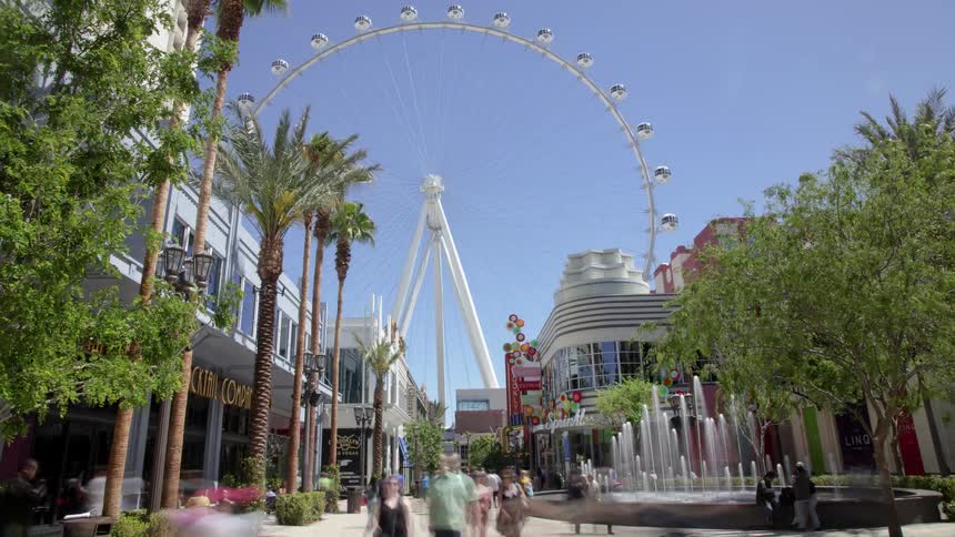 A busy walkway in the city with a ferris wheel in the background