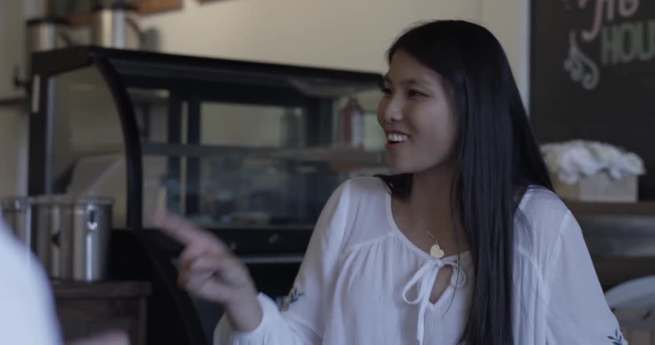 A woman is arguing and smiling conversing about stuff at a cafe table