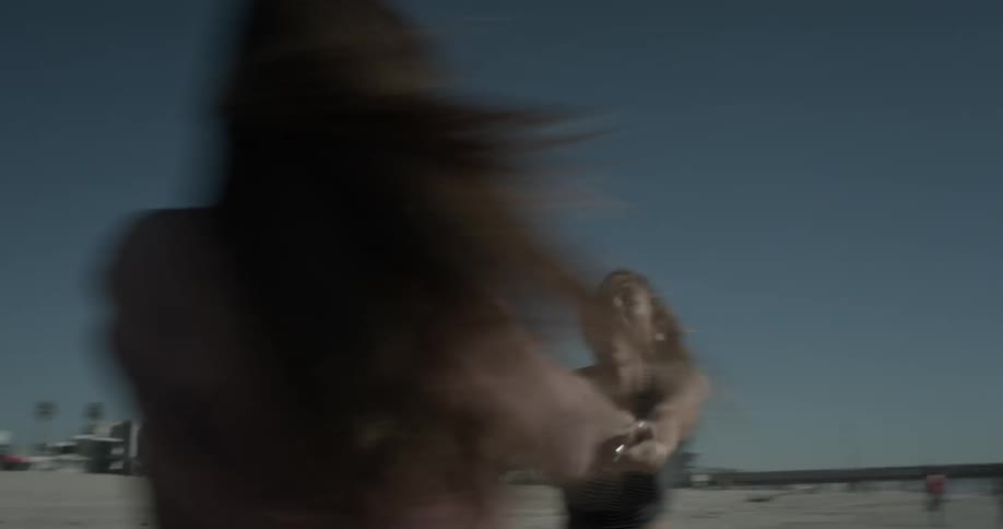 Two girls twirl around holding hands on a beach