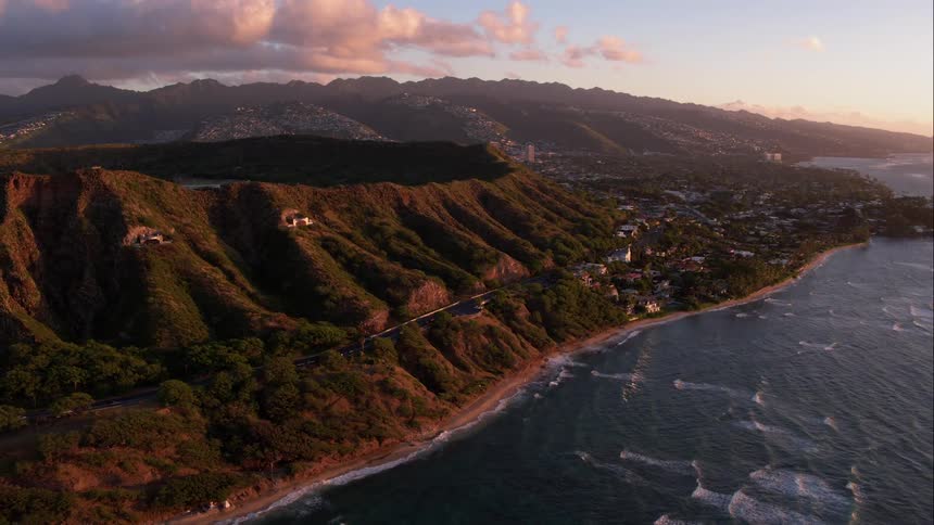 Aerial shot of hills and a road next to the ocean