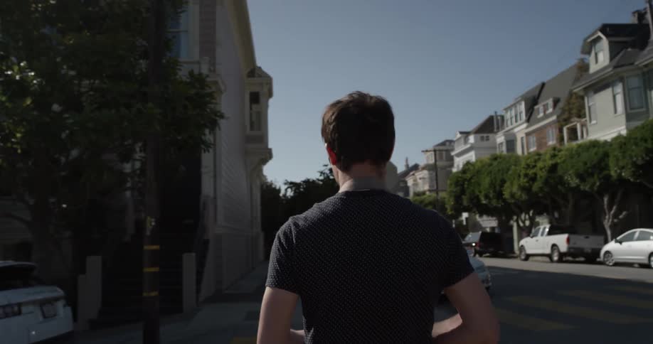 Man walks across a city street on a sunny day