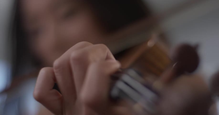 Woman plays the violin moving her fingers and the bow