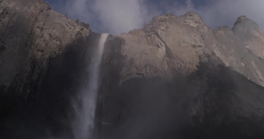 A very large waterfall on a cliff side on a sunny day