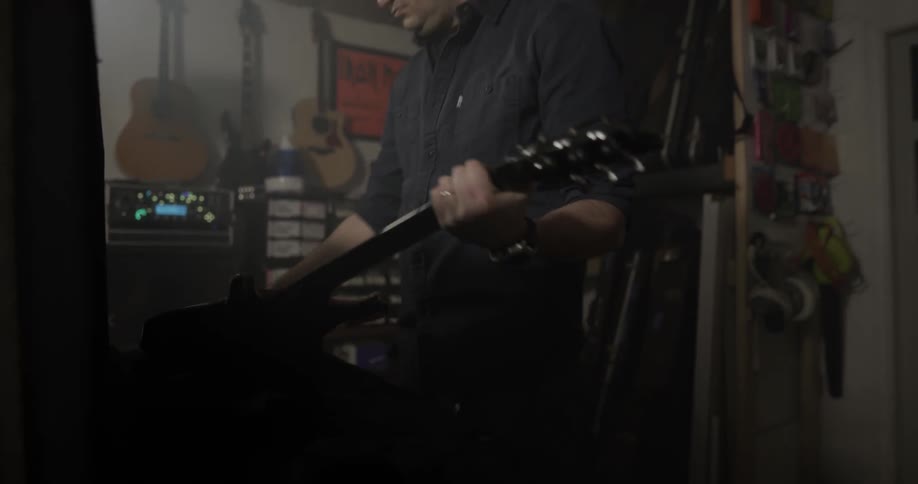 A man opens a large guitar case and pulls the guitar contained within out of it